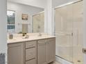 Well-lit bathroom with double vanity, sleek countertops, and a glass-enclosed shower stall at 329 Brockbank Pl, Henderson, NV 89011