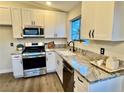 Updated kitchen with granite countertops, stainless steel appliances, and white cabinets, offering a modern aesthetic at 407 Tiger Lily Way, Henderson, NV 89015