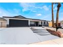 Inviting single-story home featuring a dark-gray two-car garage and low maintenance desert landscaping at 4442 Bennett Dr, Las Vegas, NV 89121