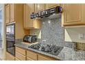 Close up of kitchen featuring a gas range, granite countertops and maple cabinets at 5833 Craigmore Ln, North Las Vegas, NV 89031