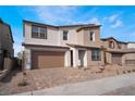 View of the home featuring a two-car garage, covered entryway, and simple landscaping with stone and sparse foliage at 785 Black Palace St, Henderson, NV 89011