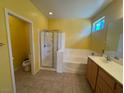 Bright bathroom with a walk-in shower, separate bathtub and a double sink vanity with wood cabinets at 8325 Aspen Village St, Las Vegas, NV 89113