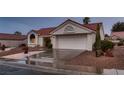Single-story home with red tile roof, desert landscaping, and an attached two-car garage at 8613 Linderwood Dr, Las Vegas, NV 89134