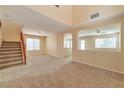 Open-concept living area featuring carpet flooring, neutral walls, and staircase to the second floor at 9324 Freedom Heights Ave, Las Vegas, NV 89149