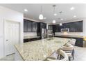 A kitchen with dark cabinets, stainless appliances, and granite counters with a large island and barstool seating at 10742 Cowlite Ave, Las Vegas, NV 89166