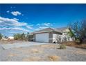 A single-story home boasts a clean two-car garage and low maintenance desert landscaping at 1351 Fawn St, Pahrump, NV 89048