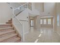 Bright foyer with tile floors, a staircase with glass railings, and an abundance of natural light at 1812 Relate Ct, Las Vegas, NV 89117
