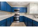 Well-lit kitchen featuring vibrant blue cabinets, tile floors, stainless steel appliances, and practical counter space at 350 S Durango Dr # 108, Las Vegas, NV 89145