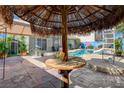 Unique patio space with thatched umbrella and custom stamped concrete near the backyard pool at 3832 Alder Creek Ct, North Las Vegas, NV 89032
