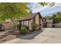 Exterior view of a townhome featuring an attached garage, mature trees, and a well-kept yard at 4571 Sirius Ave, Las Vegas, NV 89102