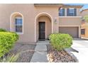 Charming home entrance with a well-manicured front yard and arched doorway at 7115 Hickory Post Ave, Las Vegas, NV 89179