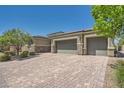 Large paver driveway leading to a three-car garage with stone accents on a sunny day at 7340 Zonal Ave, Las Vegas, NV 89131