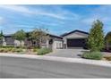Charming single-story house featuring neutral tones, a dark garage door, and manicured shrubs at 7416 Deschutes Cir, Las Vegas, NV 89129
