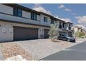 Townhome exteriors with private garages and driveways offer convenient parking and a well-maintained community aesthetic under a sunny sky at 835 Jigglypuff Pl, Henderson, NV 89011