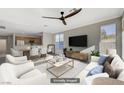 Staged living room flows into the kitchen and dining area with lots of natural light, stylish furnishings, and a ceiling fan at 10201 Premia Pl, Las Vegas, NV 89135