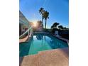 Backyard pool with lounge chairs and mature palm trees under a bright blue sky at 2016 Catalina Marie Ave, Henderson, NV 89074
