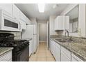 Galley kitchen features granite countertops, white cabinets, and black appliances at 2200 S Fort Apache Rd # 1033, Las Vegas, NV 89117