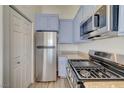 Well-lit kitchen with stainless steel appliances and ample blue cabinet space at 3318 N Decatur Blvd # 2129, Las Vegas, NV 89130