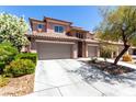 Two-story home featuring a tile roof, stone accents, a two-car garage, and desert landscaping at 3408 Livia Ave, North Las Vegas, NV 89031