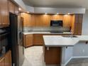 Spacious kitchen with wooden cabinets, a center island, tile countertops, and stainless steel appliances at 4121 Erinbird Ave, North Las Vegas, NV 89084