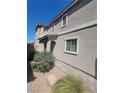 Side exterior view of a two-story home featuring neutral stucco, brick walkway and manicured landscaping at 44 Moon Hill Dr, Henderson, NV 89011