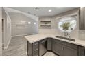 Open-concept kitchen with stainless steel appliances, gray cabinets, quartz countertops, and seamless flow into the living area at 5018 S Rainbow Blvd # 202, Las Vegas, NV 89118
