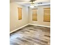 Bright bedroom featuring three windows with wood blinds, a ceiling fan, and modern gray-toned floors at 5055 Lime Kiln Ave, Las Vegas, NV 89139