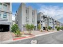 Street view of modern townhomes features desert landscaping, brick-paved driveways, and gray concrete exteriors at 8056 Haywood Estate Ave, Las Vegas, NV 89113