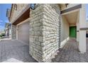 Close-up of a home's stone facade, a two-car garage, and a green front door at 387 Larksong Ave, Henderson, NV 89011