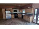 Rustic kitchen with wooden cabinets, black appliances, and durable tiled floors at 5450 Humbolt Pl, Pahrump, NV 89060