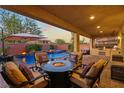 Inviting covered patio featuring a fire pit, built in grill, pool and lounge seating at 7322 Columbia Rock Ct, Las Vegas, NV 89178