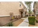 Close up of the tan siding of a townhouse with gravel landscaping and a sidewalk at 8675 Traveling Breeze Ave # 101, Las Vegas, NV 89178