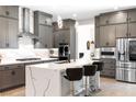 A modern kitchen features gray cabinets, stainless steel appliances, a waterfall island, and pendant lighting at 8929 Cassia Winds St, Las Vegas, NV 89166