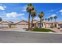 Inviting single-story home with a three-car garage, desert landscaping, and mature palm trees enhancing curb appeal at 9096 Nomo St, Las Vegas, NV 89123