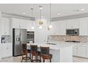 Modern kitchen with white cabinets, stainless steel appliances, and an island with bar stools at 10127 Knotty Skye Ave, Las Vegas, NV 89166