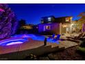Night view of the pool and spa with custom chairs, landscaping, and lighting at 10520 Maystar Ln, Las Vegas, NV 89135