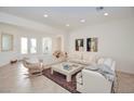 Bright living room with neutral decor, tile flooring, and a comfortable seating arrangement perfect for relaxation at 10573 Bambola Pl, Las Vegas, NV 89135