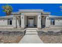 Close up of the front entrance featuring an arched entryway, pillars and desert landscaping at 1420 Logandale Dr, Logandale, NV 89021