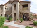 Exterior view of a tan two-story condo building with a stairwell to the second level and desert landscaping at 2110 Los Feliz St # 1083, Las Vegas, NV 89156