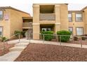An exterior view of a condo building with landscaping, access ramps and stairs at 2300 E Silverado Ranch Blvd # 1070, Las Vegas, NV 89183