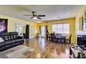 Bright living room with wood-look laminate flooring, ceiling fan, and a large front-facing window at 513 Berry Cir, Las Vegas, NV 89107
