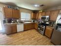 Well-lit kitchen features wooden cabinets, modern appliances, and laminate wood flooring at 5281 Starter Ave, Las Vegas, NV 89156