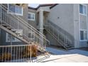 Modern condo with gray stucco, white trim, and staircase leading to upper units and walkways at 6160 Rumrill St # 121, Las Vegas, NV 89113