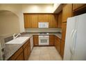 Cozy kitchen with wood cabinets, granite counters, and modern white appliances at 62 E Serene Ave # 129, Las Vegas, NV 89123