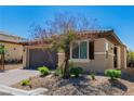 Single story home featuring desert landscaping, a gray two car garage, and a drought-tolerant tree at 6829 Painted Morning Ave, Las Vegas, NV 89142