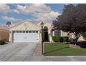 Inviting home featuring a well-manicured lawn, mature tree, and a two-car garage at 7697 Morning Lake Dr, Las Vegas, NV 89131