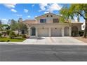 Traditional two-story home with a two-car garage, arched doorways, and fresh green landscaping at 7984 Laurena Ave, Las Vegas, NV 89147