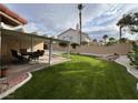 Lush backyard featuring manicured lawn, covered patio, and stylish outdoor furniture for relaxing and entertaining at 8316 Vibrant Dr, Las Vegas, NV 89117