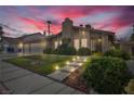 Inviting home exterior featuring a lush lawn, stone walkway, and mature landscaping at dusk at 8316 Vibrant Dr, Las Vegas, NV 89117