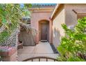 Inviting home entrance with stone facade, arched doorway, and lush landscaping at 10310 Songsparrow Ct, Las Vegas, NV 89135